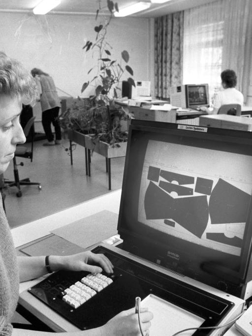 Eine Frau bei der Arbeit an einem Computer zur Optimierung des Zuschnitts von Bekleidungsteilen aus den Stoffen, aufgenommen im VEB Wäschekonfektion Lößnitz im April 1989.