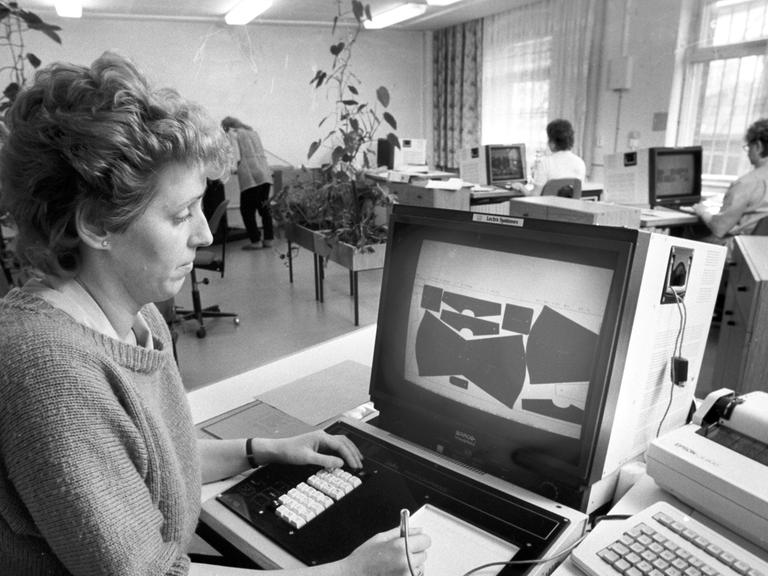 Eine Frau bei der Arbeit an einem Computer zur Optimierung des Zuschnitts von Bekleidungsteilen aus den Stoffen, aufgenommen im VEB Wäschekonfektion Lößnitz im April 1989.