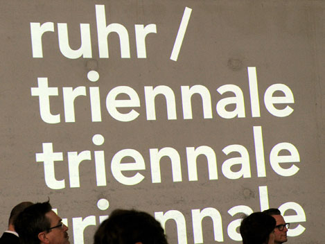 Journalisten stehen in Essen vor dem Logo des Festivals Ruhrtriennale, während der künstlerische Leiter Heiner Goebbels das neue Programm vorstellte.