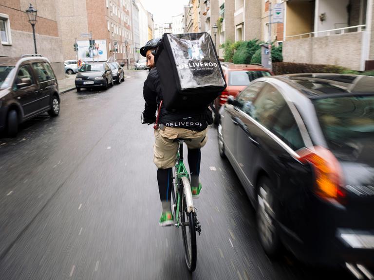 Ein Fahrradkurier ist im Auftrag der Firma Deliveroo unterwegs. Deliveroo beliefert Kunden mit Essen aus Restaurants.