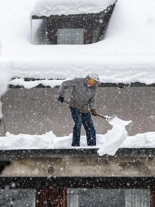 13.01.2019, Bayern, Elisabethszell: Ein Mann schaufelt Schnee von einem Dach.