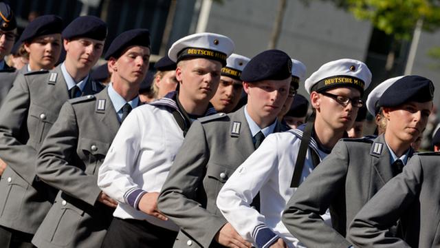 Soldaten der Bundeswehr und der Marine marschieren in einer Reihe.
