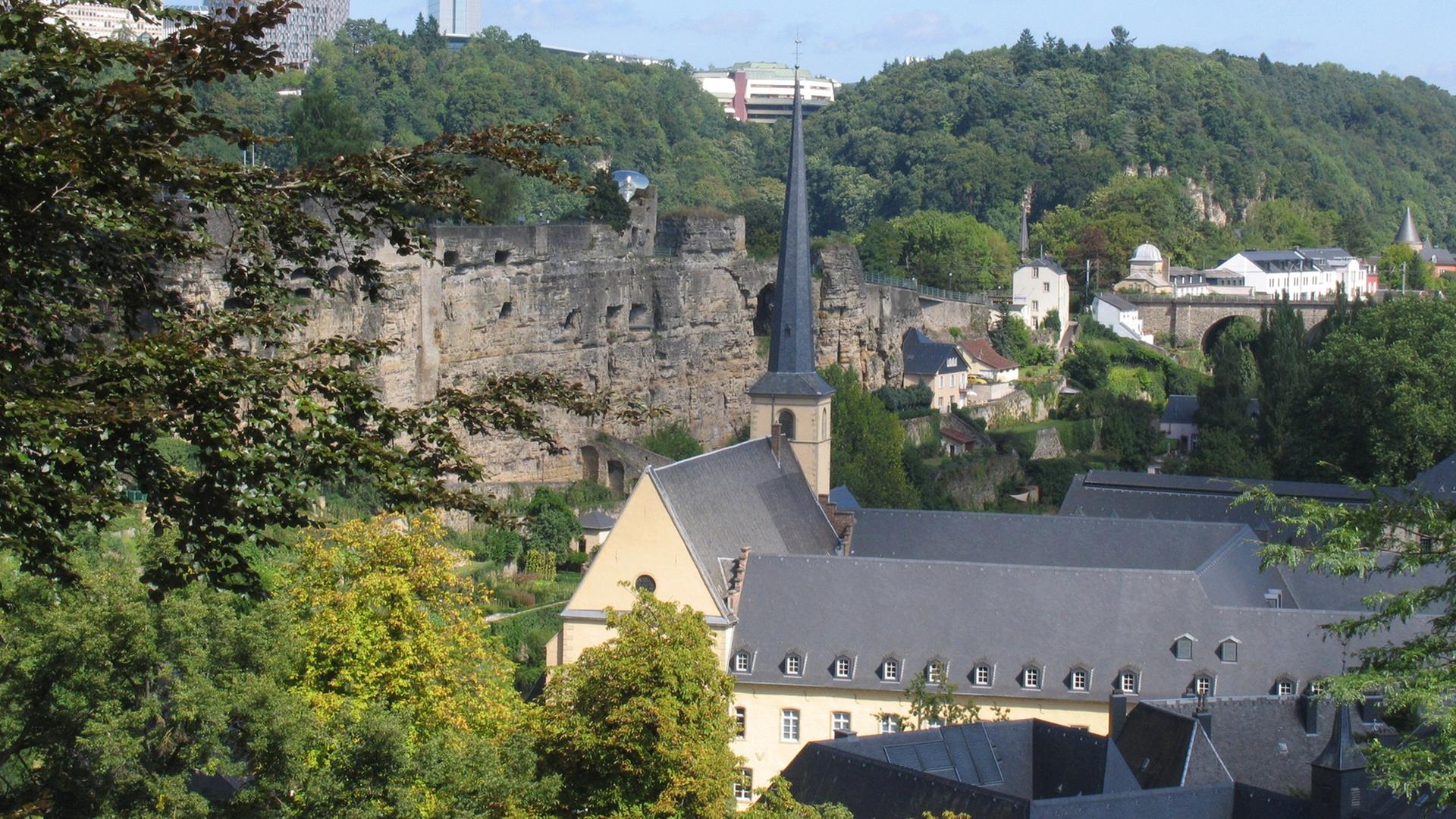 Die Burg Lucilinburhuc befindet sich in einer Höhe von rund 282 m auf dem so genannten Bockfelsen, den Graf Siegfried 963 erwarb. Darunter die Teilansicht der Kasematten. Im Hintergrund der Kirchberg mit seiner Skyline. Die Burg wird in einer Urkunde erwähnt, welche den Tausch zwischen dem Ardennergraf Siegfried und dem Kloster St. Maximin in Trier aus dem Jahre 963 dokumentiert. Aus dem Besitz des Klosters erhält der Graf den Bockfelsen gegen Ländereien in Feulen.