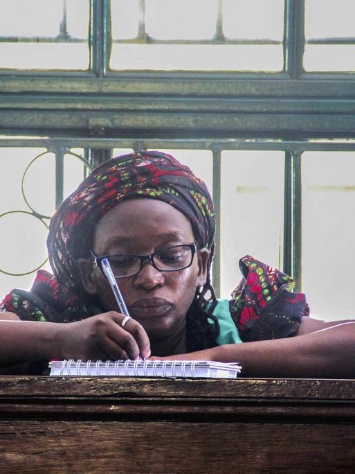 Die prominente Feministin und LGBT-Aktivistin Stella Nyanzi sitzt im Gerichssaal bei Ihnen Anhörung und macht sich Notizen in einen Ringblock.