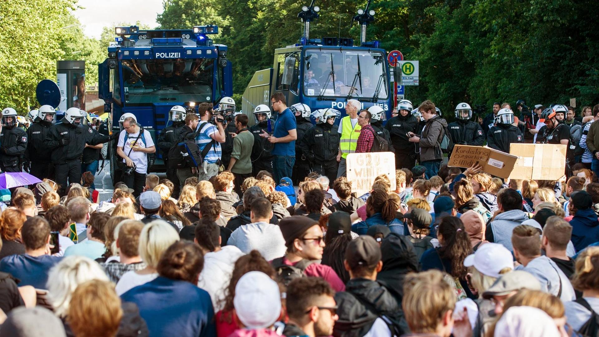 Teilnehmer einer Sitzblockade sitzen am 8. Juli 2017 in Hamburg nach der Demonstration "Grenzenlose Solidarität statt G20" Polizisten mit zwei Wasserwerfern gegenüber. Der G20-Gipfel der Staats-und Regierungschefs fand am 7. und 8. Juli 2017 in Hamburg statt. Bei den Demonstrationen gegen den Gipfel kam es zu schweren Krawallen.