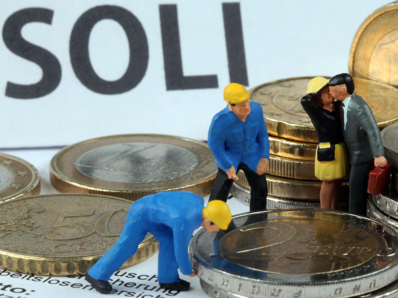 Modellfiguren inmitten von Euromünzen, im Hintergrund steht "Soli" geschrieben.