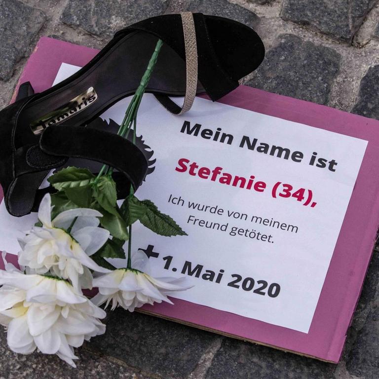 Proteste gegen Femizide: Auf einem Schild steht "Mein Name ist Stefanie (34) ich wurde von meinem Freund getötet". Daneben liegt auf dem Boden ein Schuh und eine weiße Blume.