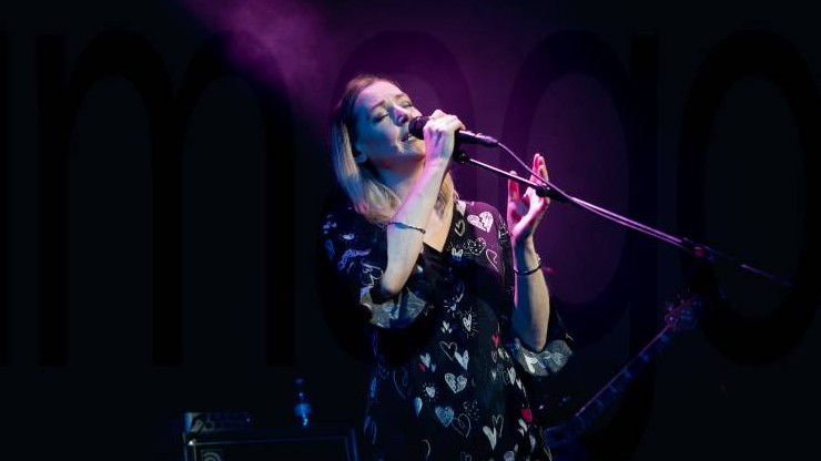 Eine Frau steht auf einer Bühne und singt in ein Mikrofon