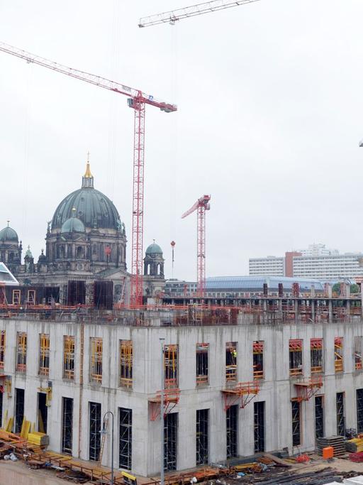 Kräne stehen auf der Baustelle des Berliner Schlosses - Humboldtforum in Berlin. Im Hintergrund ist der Berliner Dom zusehen.