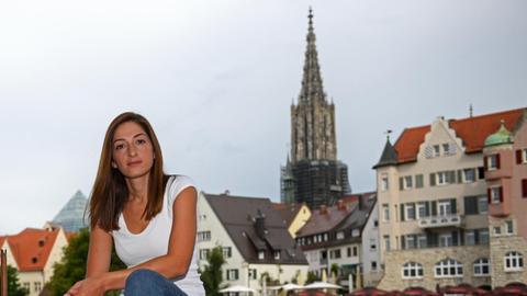 Mesale Tolu sitzt auf einem Geländer vor der Ulmer Altstadt.