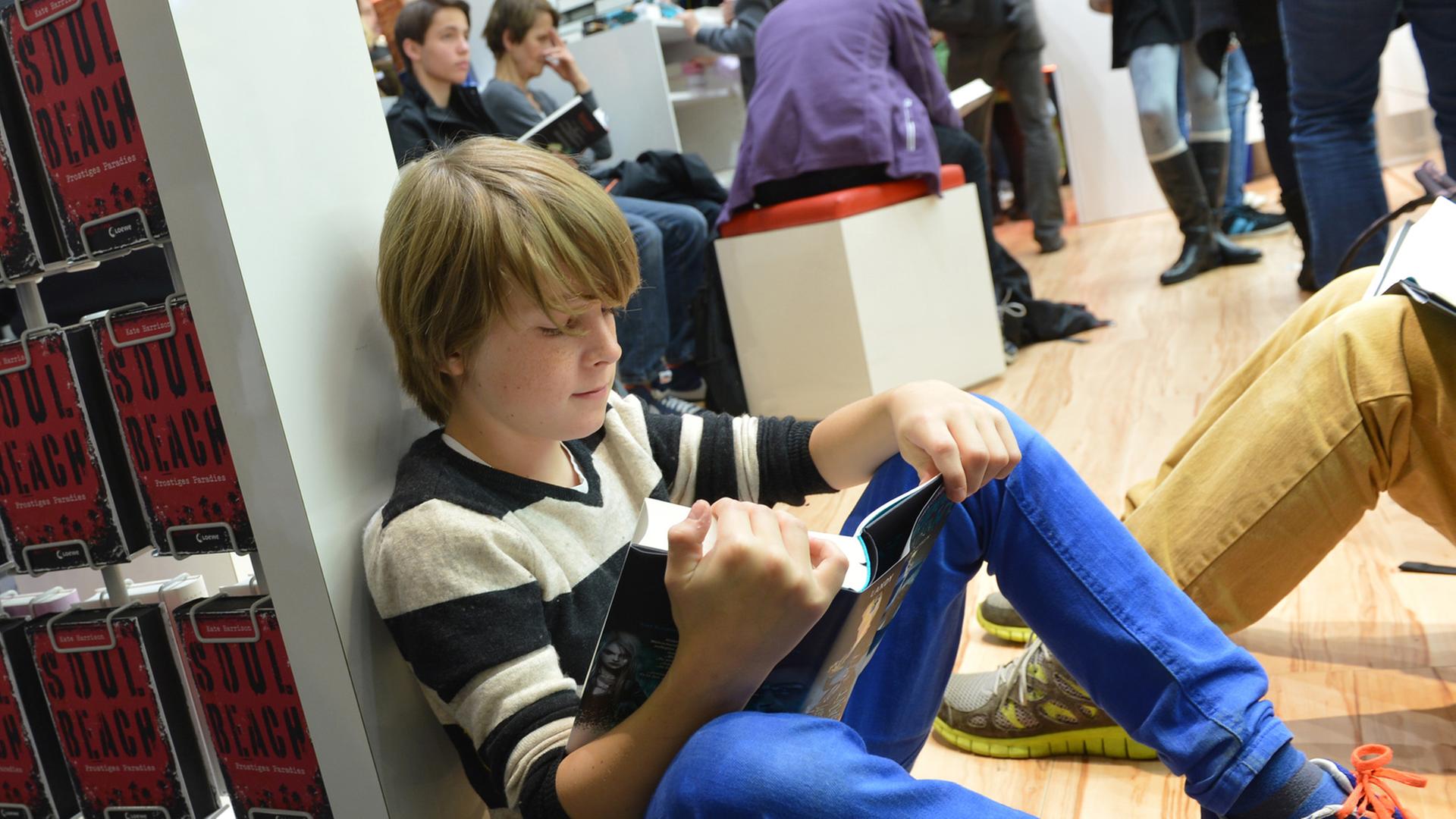 Ein Junge liest auf der Frankfurter Buchmesse 2013 ein Jugendbuch.