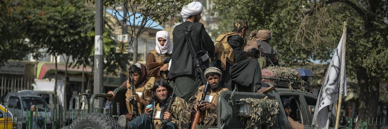 Taliban-Kämpfer patrouillieren in einem Auto entlang einer Straße.