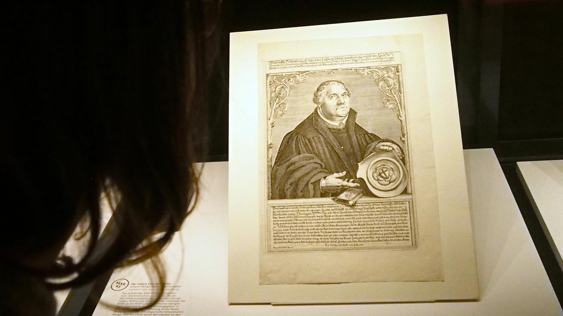 Eine Frau betrachtet in der Herzog August Bibliothek Wolfenbüttel in der Ausstellung "Luthermania - Ansichten einer Kultfigur" ein Porträt von Martin Luther.