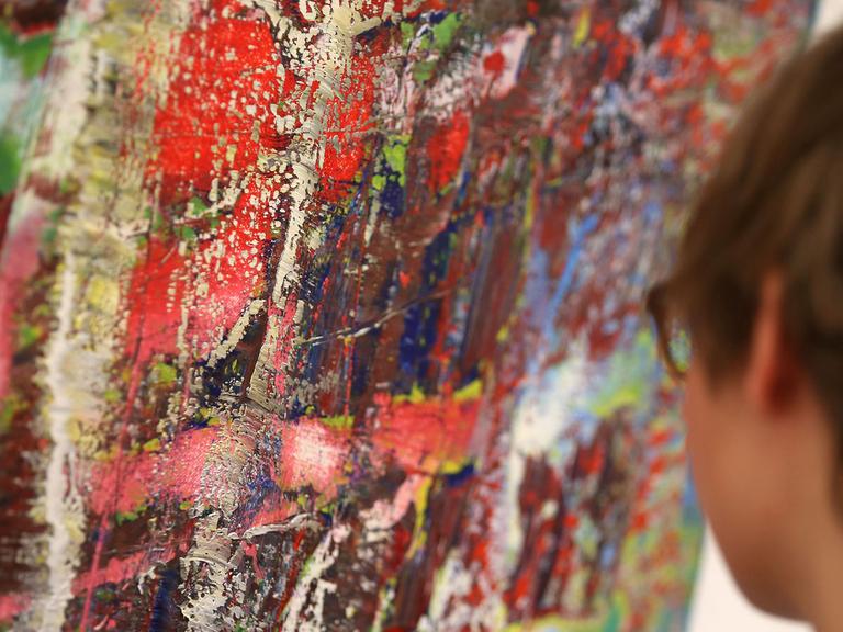 Eine Frau betrachtet ein Gemälde des Malers Gerhard Richter.