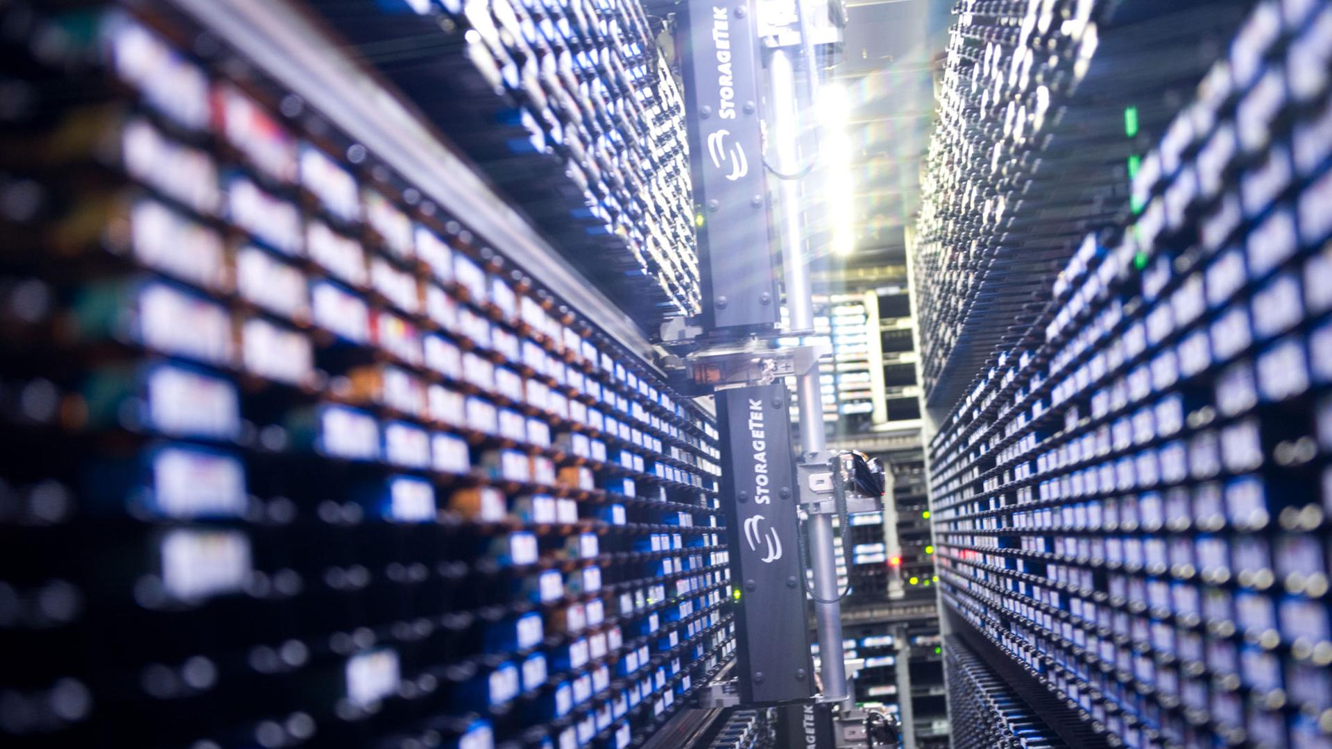 Lange Reihen von Lichtern laufen in der Mitte des Bildes zusammen. Es zeigt ein automatisches Lager für Magnet-Datenbänder in einem Nebenraum des Supercomputers "Blizzard" im Deutschen Klimarechenzentrum in Hamburg