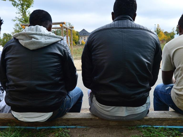 Vier junge Männer aus Eritrea sitzen am 06.10.2015 in Saalfeld in Thüringen vor einer Flüchtlingsunterkunft.