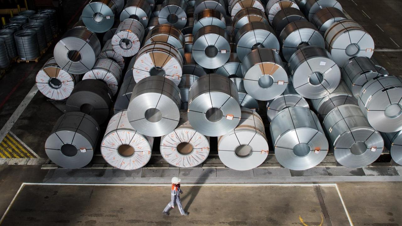Das Bild zeigt eine Mitarbeiterin auf dem Gelände der Salzgitter AG vor Coils vorbei, also vor großen Rollen aufgewickelter Metallbänder. Das Bild zeigt eine Mitarbeiterin auf dem Gelände der Salzgitter AG vor Coils vorbei, also vor großen Rollen aufgewickelter Metallbänder.