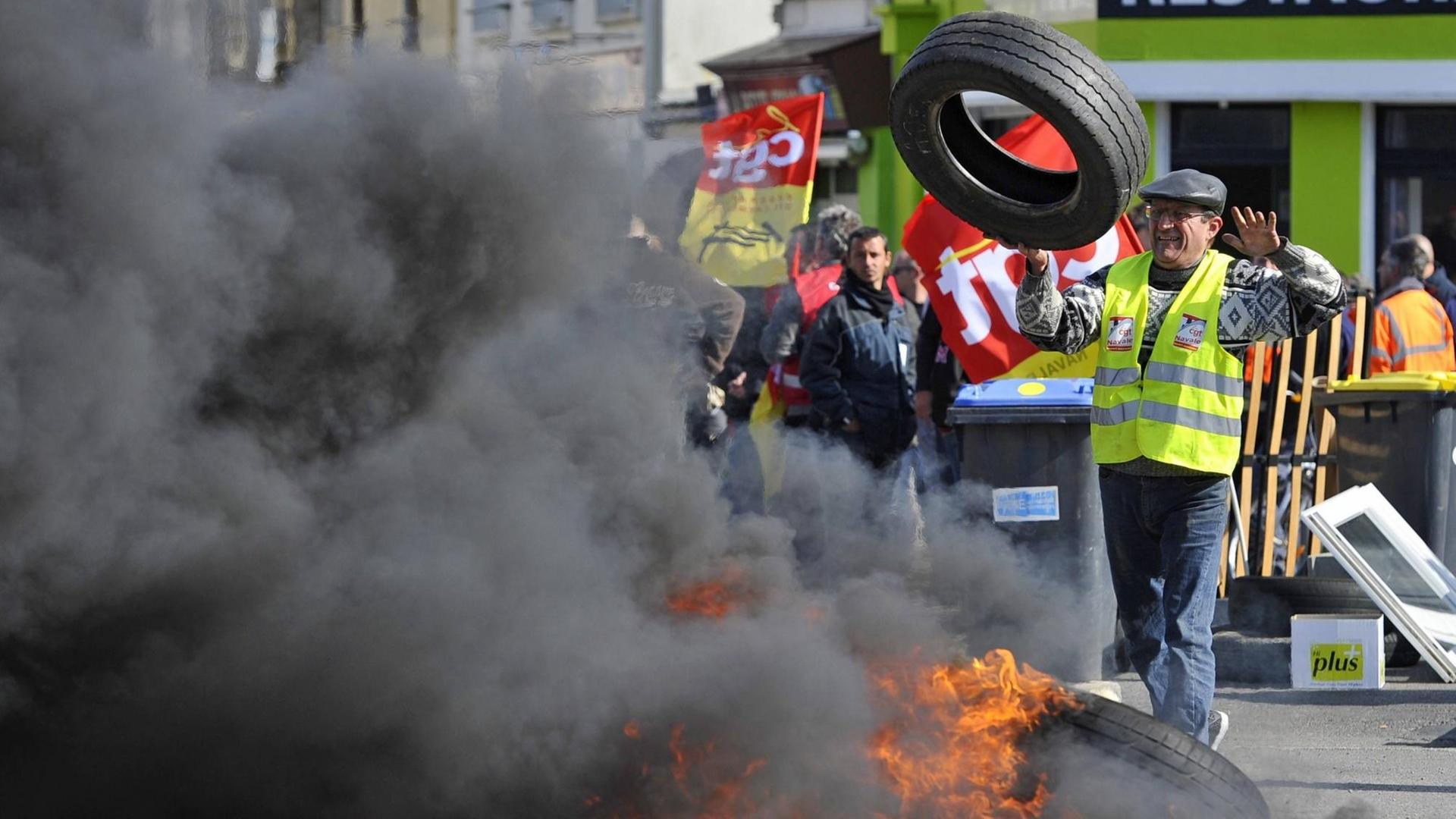 Streikende haben die Zufahrt zu einer Straße mit brennenden Autoreifen blockiert, um gegen die Arbeitsmarkt-Reform der französischen Regierung zu protestieren.