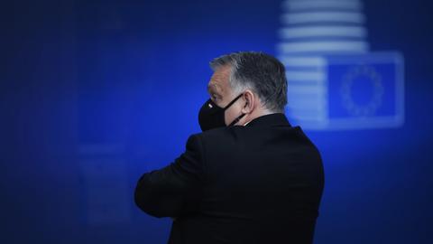 Ungarns Premier Viktor Orbán nach einem EU-Gipfel im Dezember 2020; er steht alleine mit Gesichtsmaske und wendet sich von der Kamera ab
