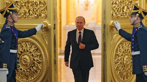 Wladimir Putin schreitet durch eine goldbesetzte Flügeltür, die ihm von zwei Uniformierten geöffnet wird, zu seiner Rede.