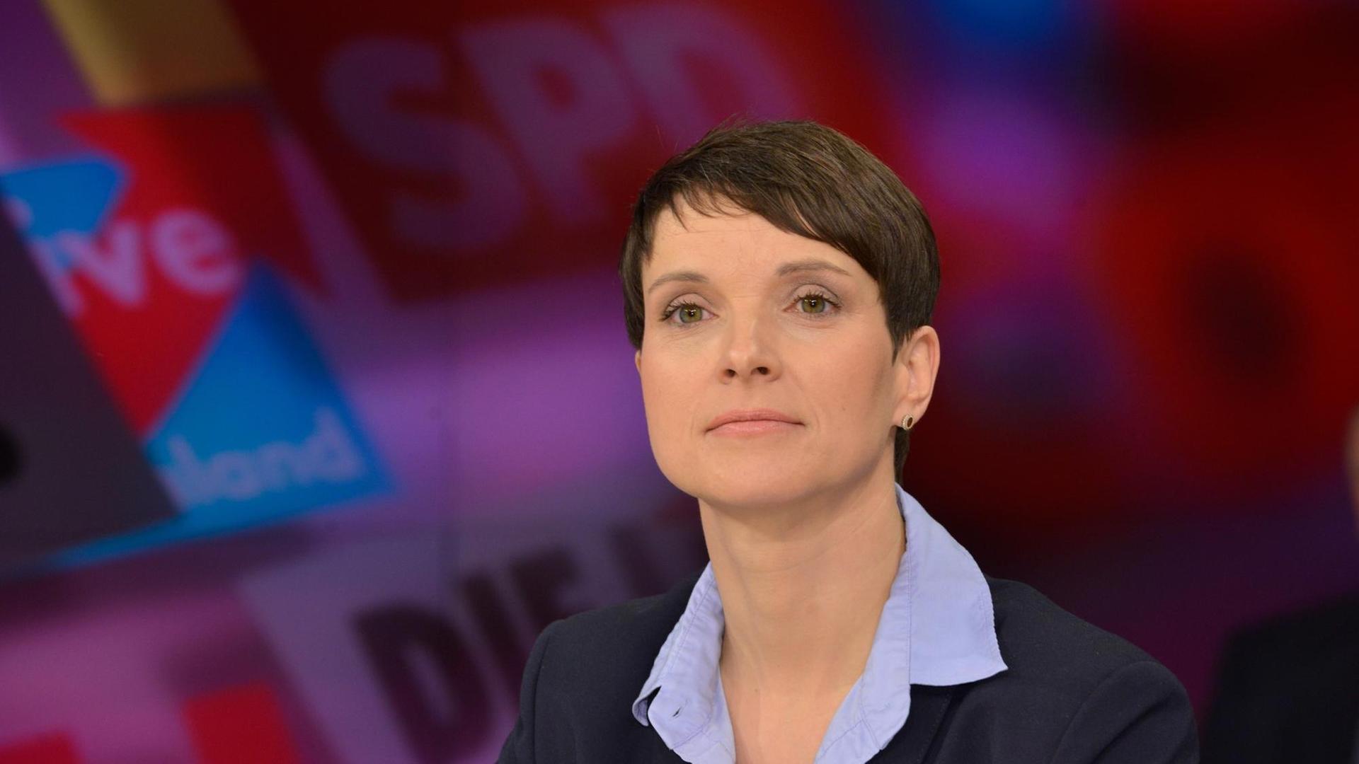 Frauke Petry, die Chefin der AfD. Auf der Wand hinter ihr stehen die Logos der großen deutschen Parteien.