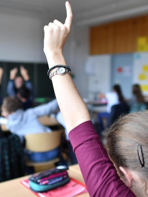 Siebtklässler strecken am 23.11.2016 während des Deutschunterrichts in einem Gymnasium in Friedrichshafen (Baden-Württemberg) ihre Hände nach oben.
