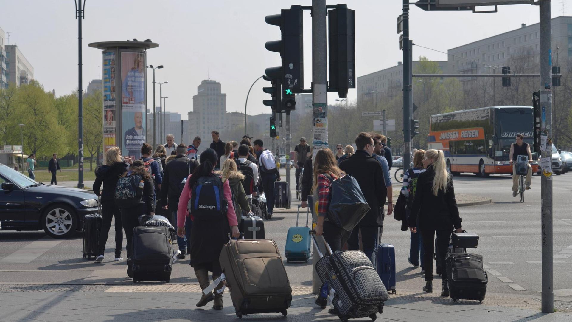Touristen ziehen am Berliner Alexanderplatz Rollkoffer hinter sich her.