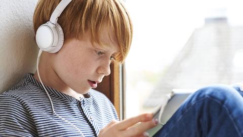 Ein Junge hört ein Podcast über einen Kopfhörer