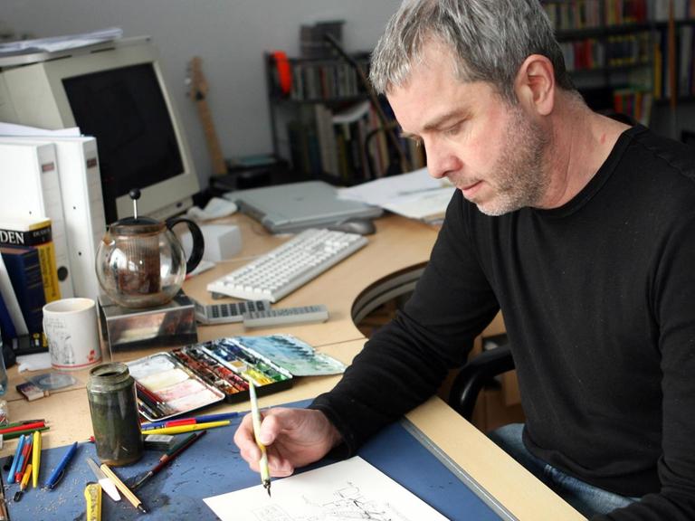 Der Karikaturist Thomas Plaßmann, aufgenommen bei der Arbeit in seinem Büro in Essen.