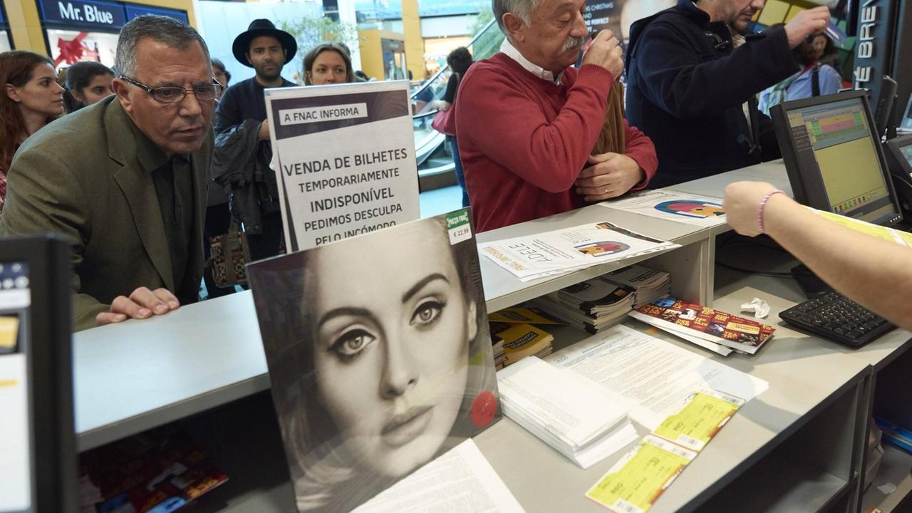 Fans der Sängerin Adele stehen an einem Ticket-Schalter, um Karten für ein Konzert zu kaufen.