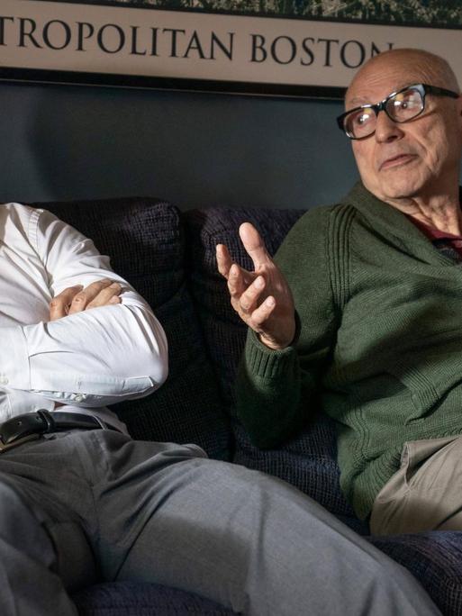 zwei Männer sitzen auf einem Sofa und unterhalten sich