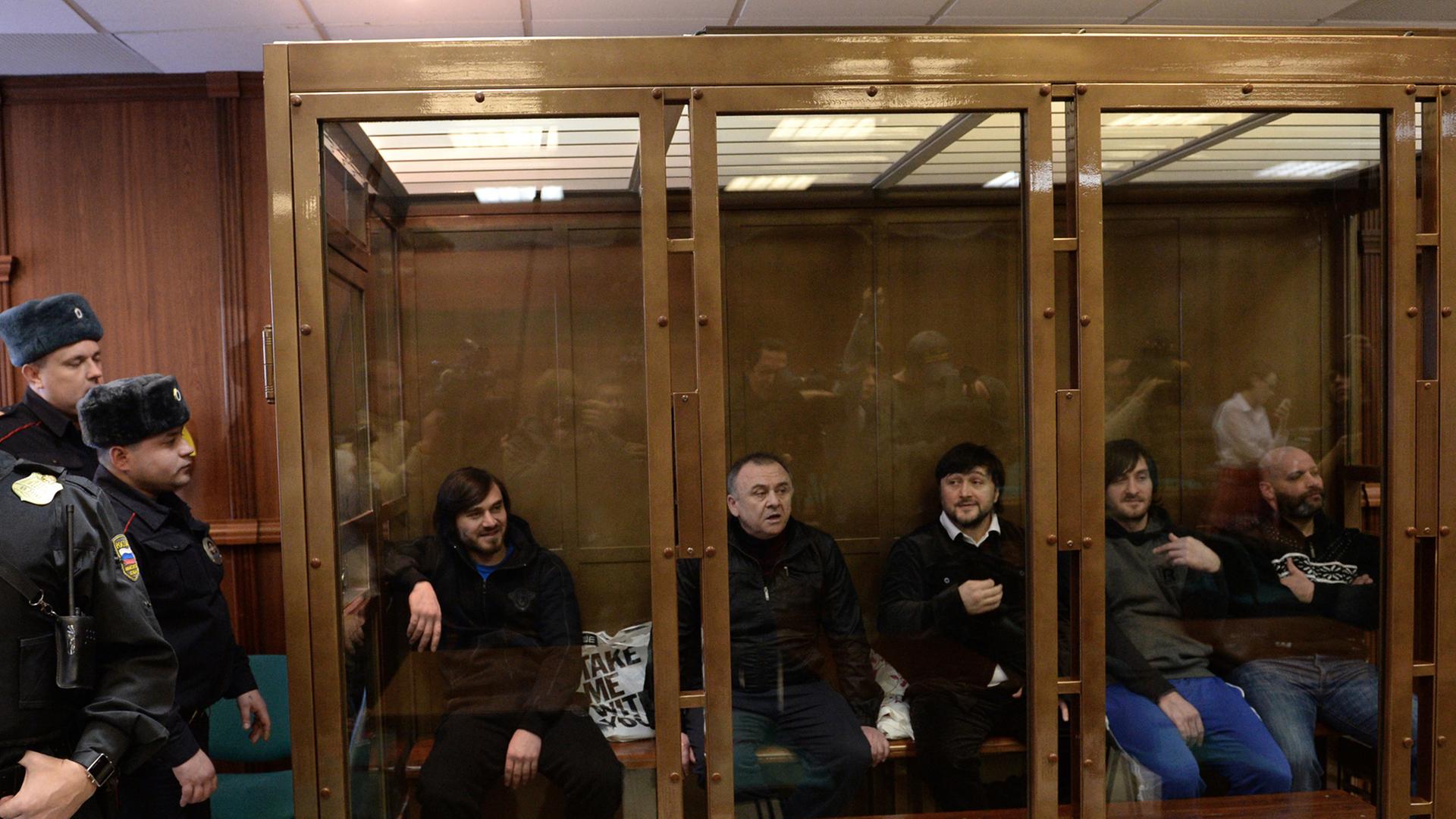 Die fünf Angeklagten im Mordfall Politkowskaja sitzen während der Verhandlungen im Glaskäfig in einem Moskauer Gericht.