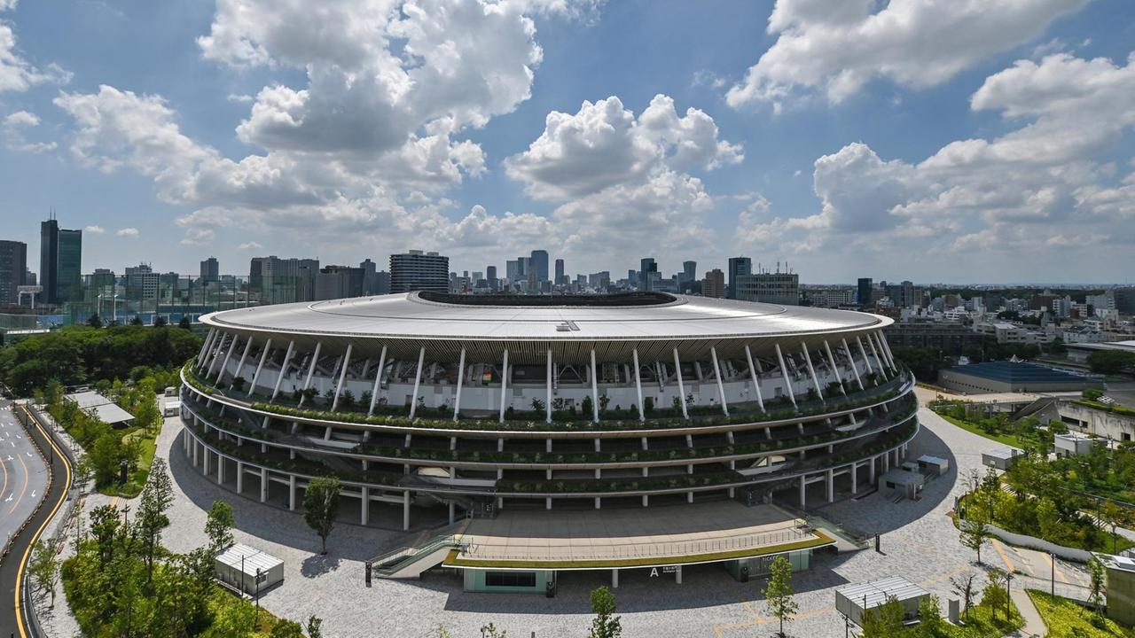 Fotografie des neu gebauten Japan National Stadium mit der Stadtsilhouette von Tokio im Hintergrund. 