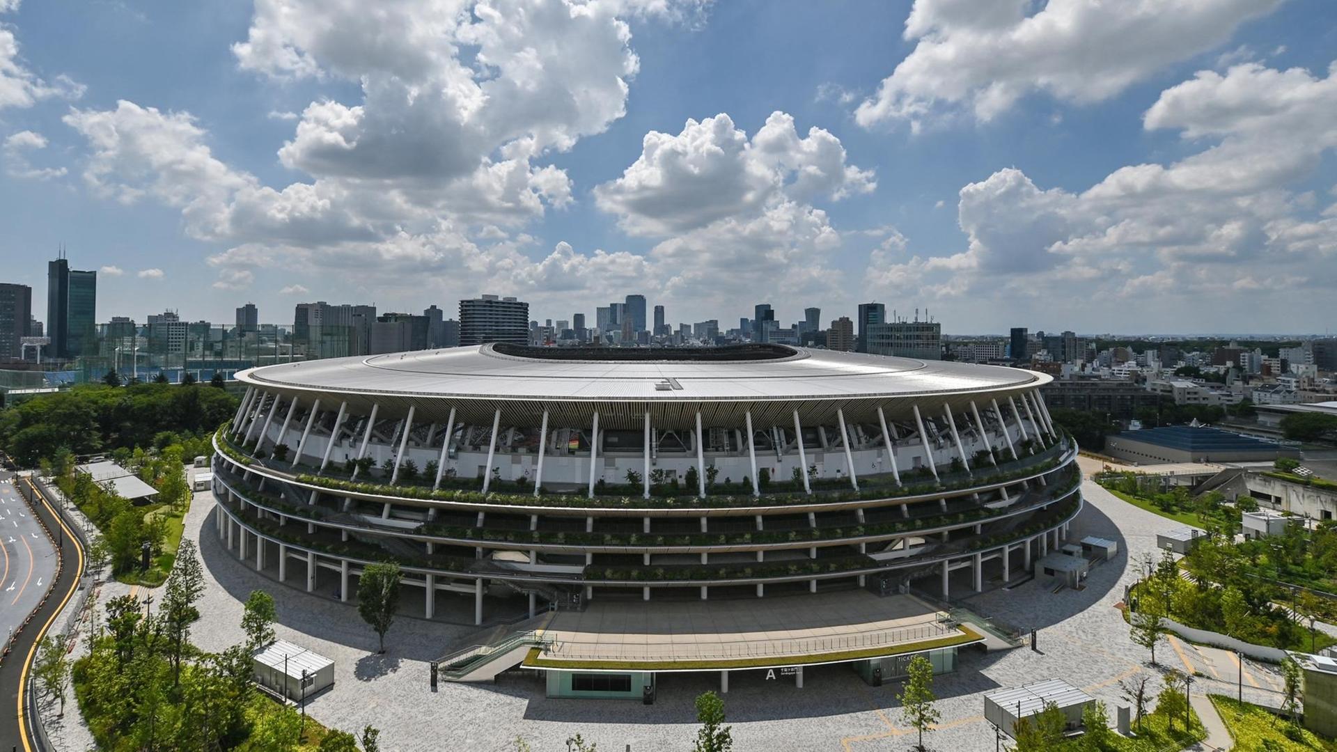 Fotografie des neu gebaute Japan National Stadiummit der Stadtsilhouette von Tokio im Hintergrund.
