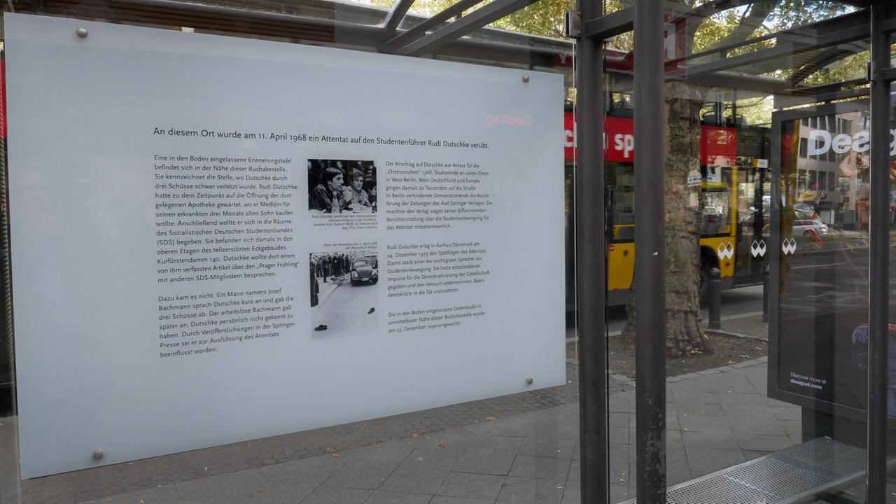 An der Rückseite einer Bushaltestelle ist eine Infotafel über Rudi Dutschke angebracht.