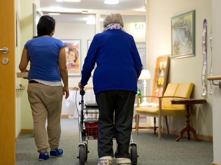 Eine Pflegerinn begleitet eine Bewohnerin eines Seniorenwohnheims