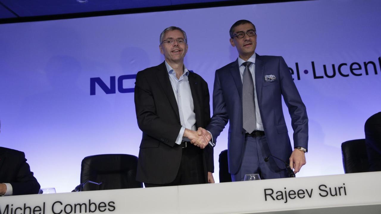 Nokia-Vorstandsvorsitzende, Rajeev Suri, und der Alcatel-Lucent-Chef Michel Combes schütteln die Hände Nokia-Vorstandsvorsitzende, Rajeev Suri, und der Alcatel-Lucent-Chef Michel Combes schütteln die Hände