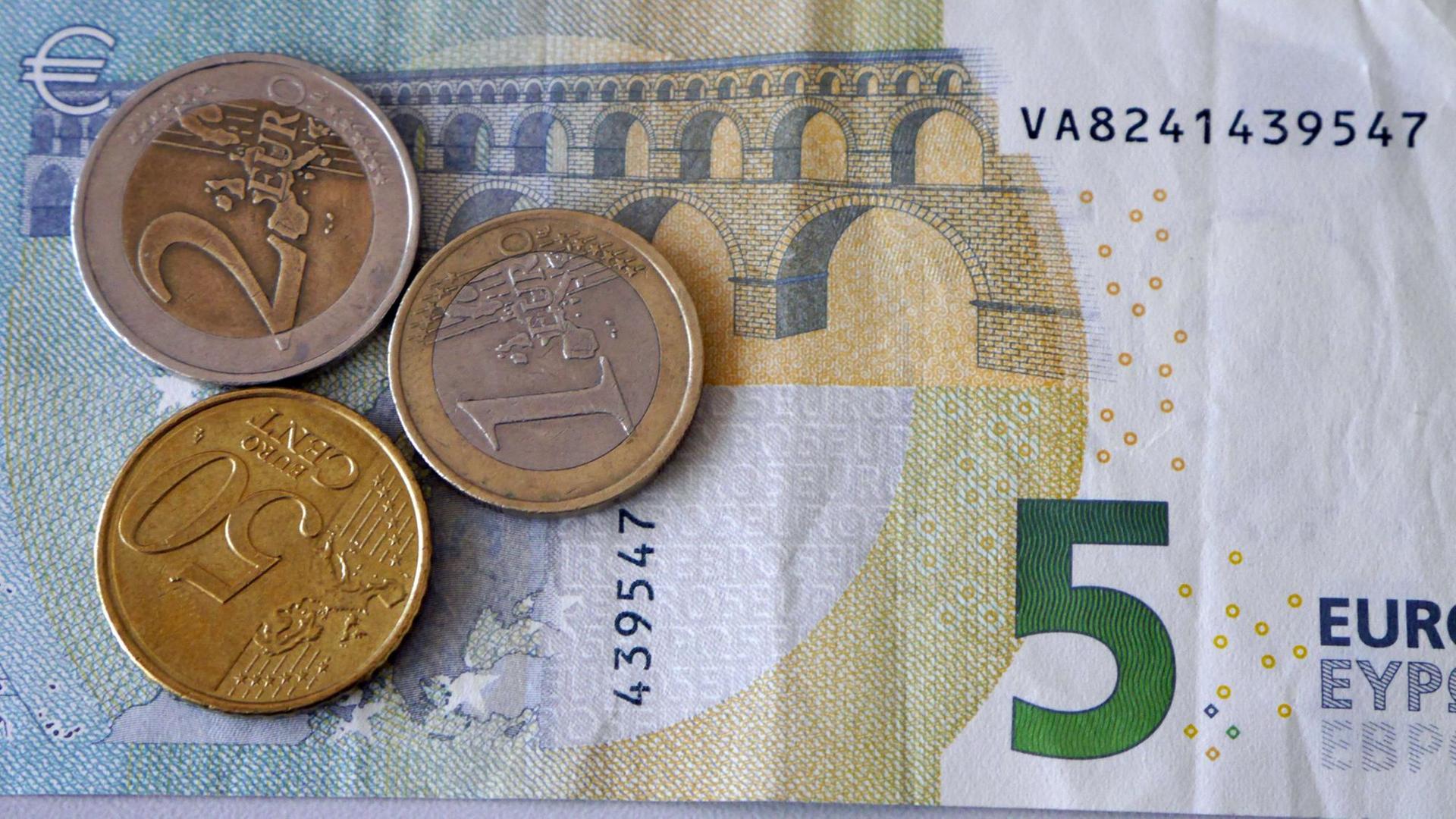 Ein Fünf-Euro-Schein liegt mit einem Ein- und Zwei-Euro und einem 50-Cent-Stück auf einem Stapel.