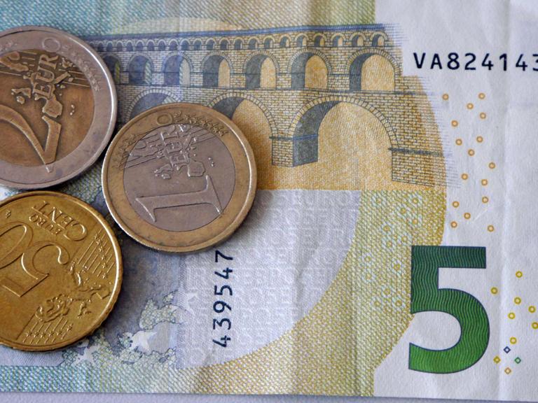 Ein Fünf-Euro-Schein liegt mit einem Ein- und Zwei-Euro und einem 50-Cent-Stück auf einem Stapel.