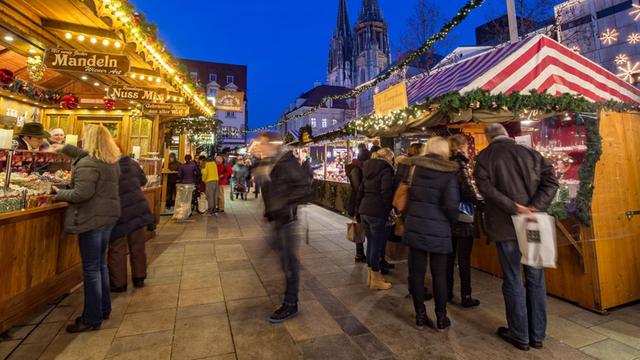 Der Weihnachtsmarkt auf dem Neupfarrplatz in Regensburg. Es ist dunkel und die Buden sind hell beleuchtet.