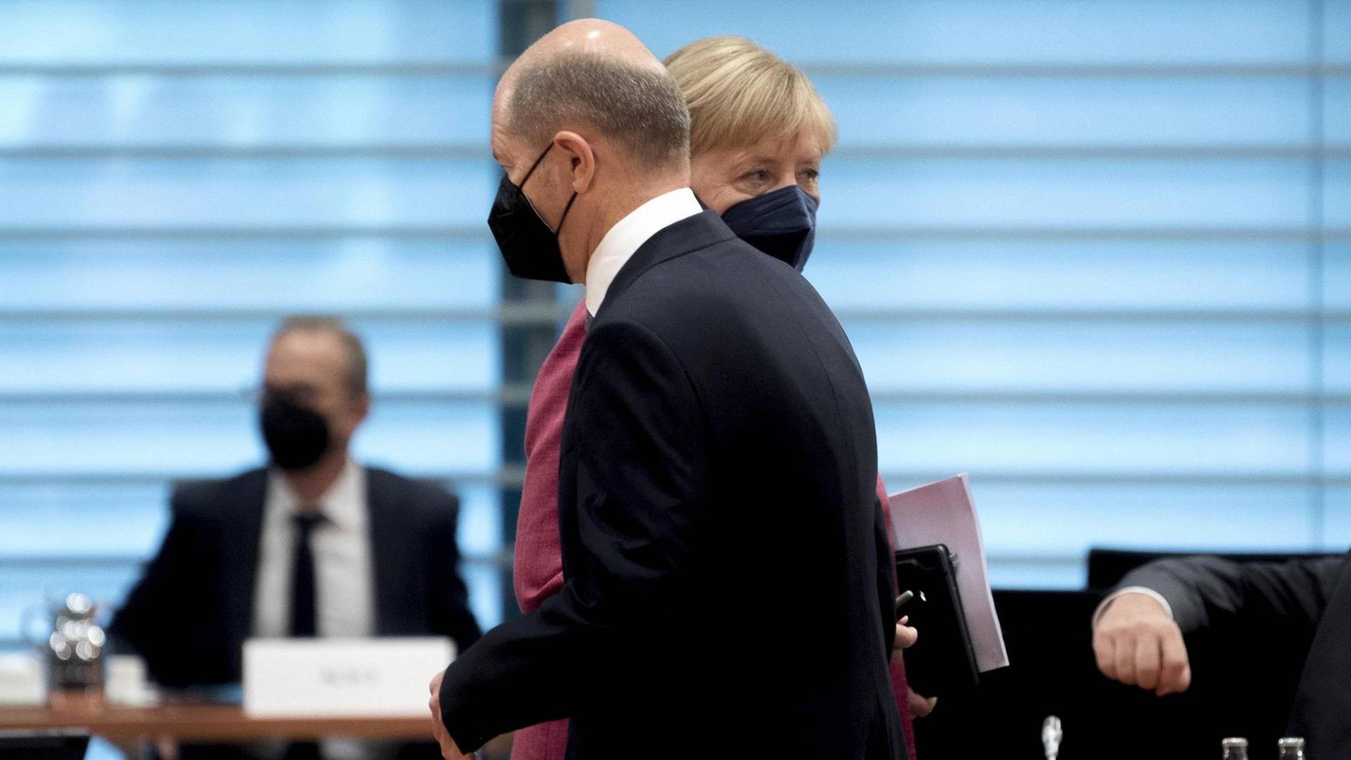 Olaf Scholz (SPD) geht in einer Kabinettsitzung an Bundeskanzlerin Angela Merkel (CDU) vorbei.