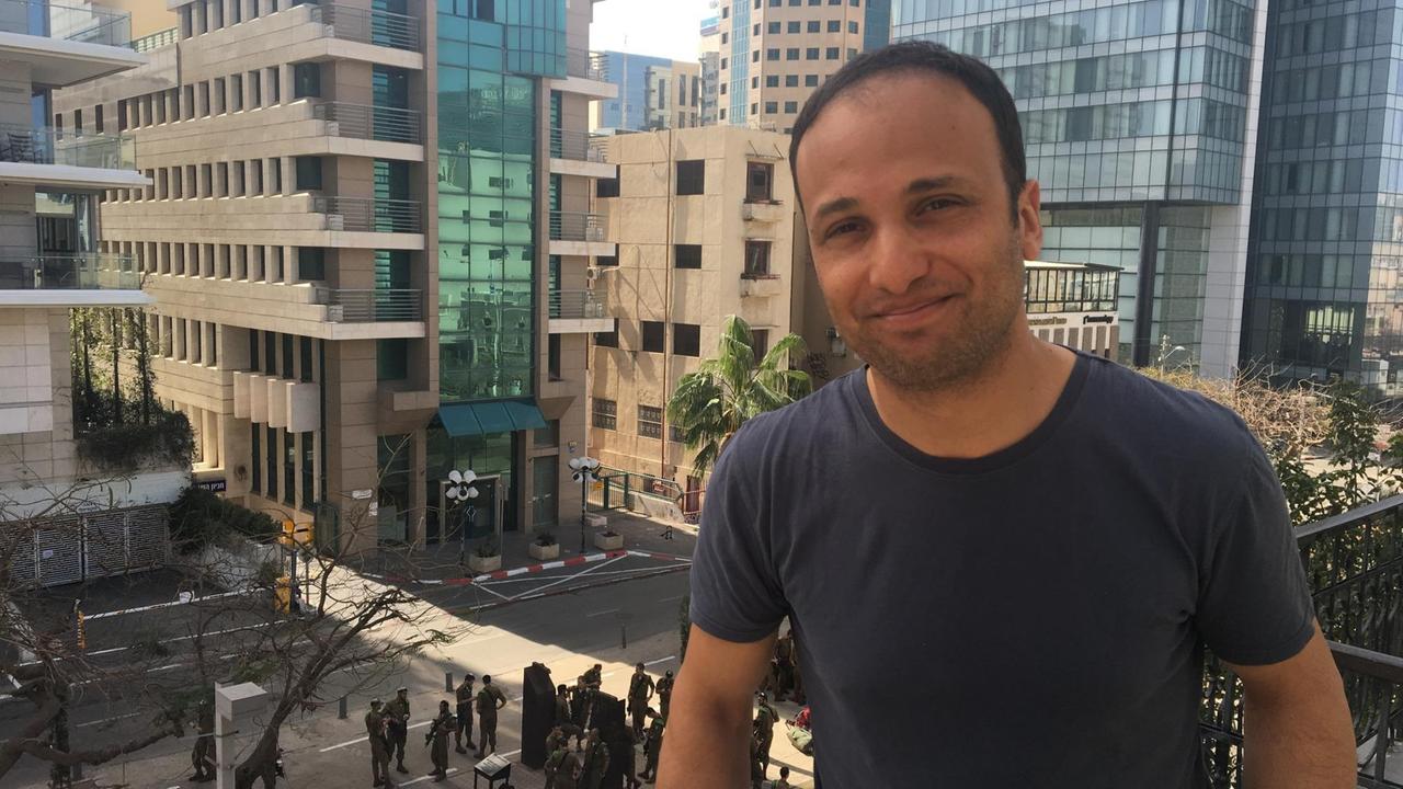 Yonatan Adiri steht vor den Glasfasaden israelische Hochhäuser.