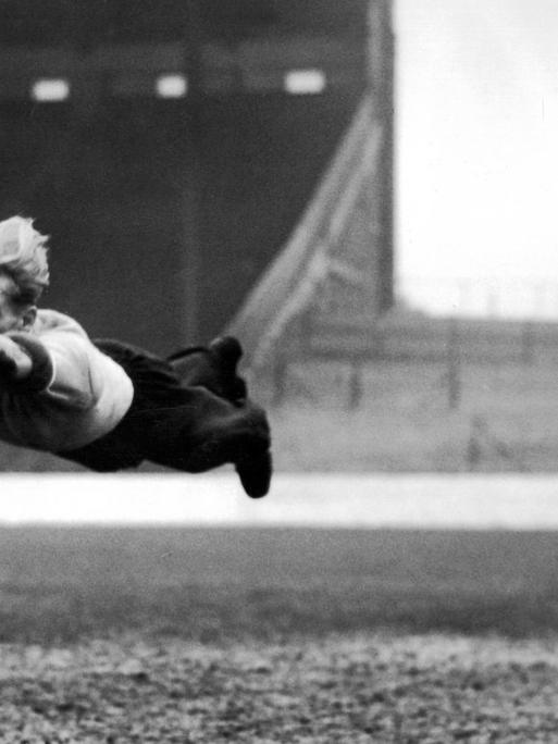 Torhüter Bert Trautmann springt einem Ball vor dem Tor hinterher. Auf dem Schwarz-Weiß-Foto aus dem Jahr 1952 liegt er waagerecht in der Luft, der Ball ist weit vor ihm.