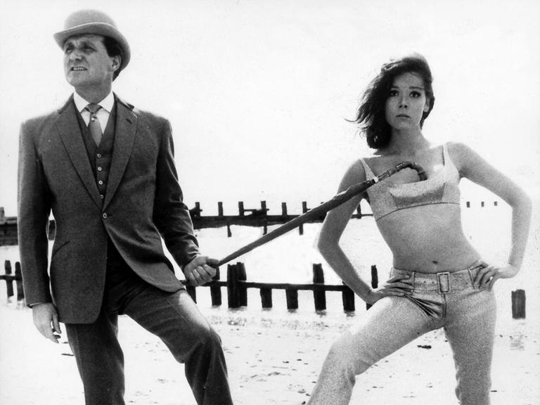 Die britische Schauspielerin Diana Rigg als Geheimagentin "Emma Peel" mit ihrem Partner John Steed, gespielt von Patrick Macnee, in der britischen Erfolgsserie "Mit Schirm, Charme und Melone". (Aufnahme von 1965).