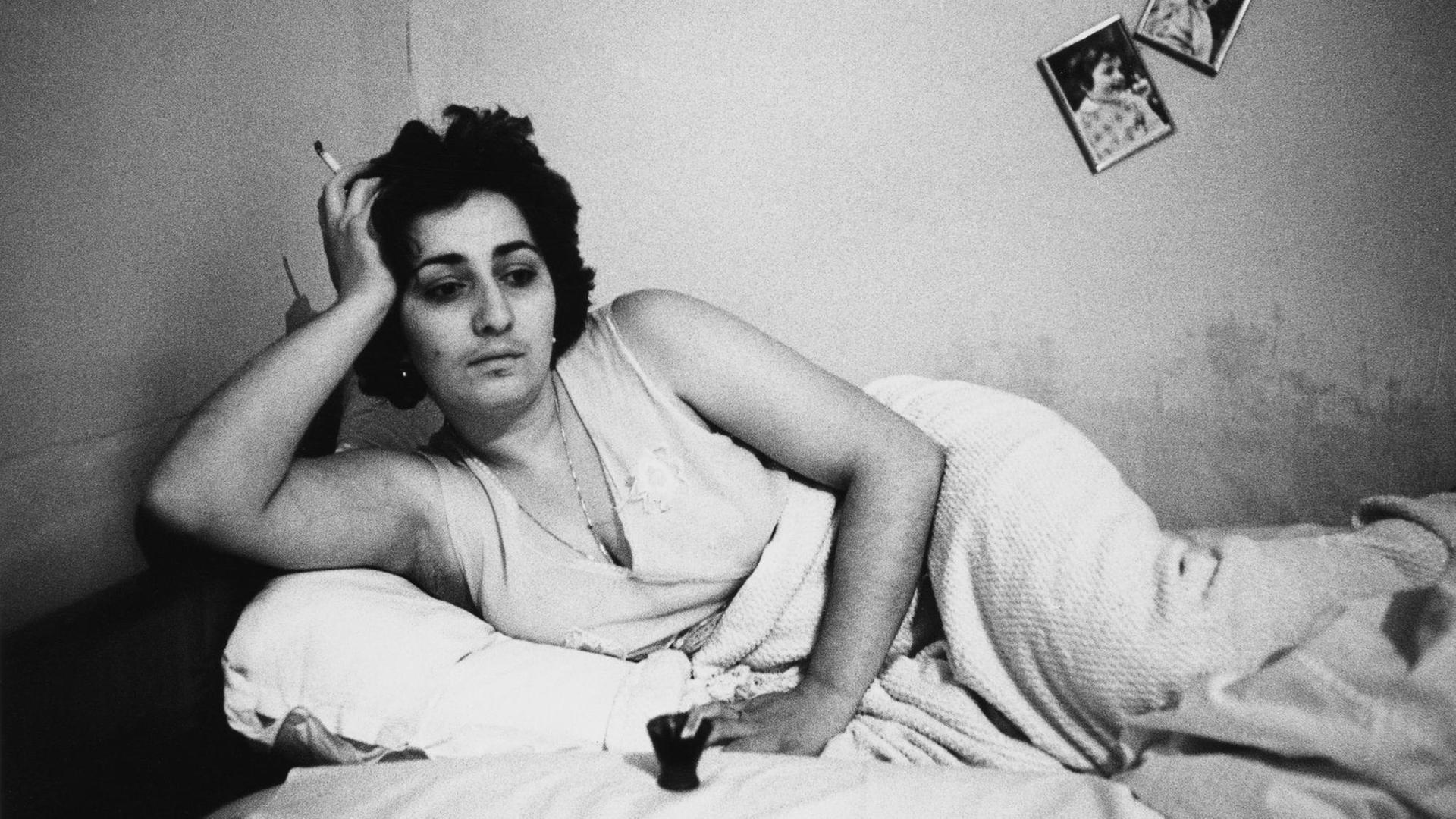 Eine Frau liegt auf einem Bett, ihre Zigarette in der Hand. Ohne Titel, aus der Serie "Georgien", 1982, von Helga Paris.