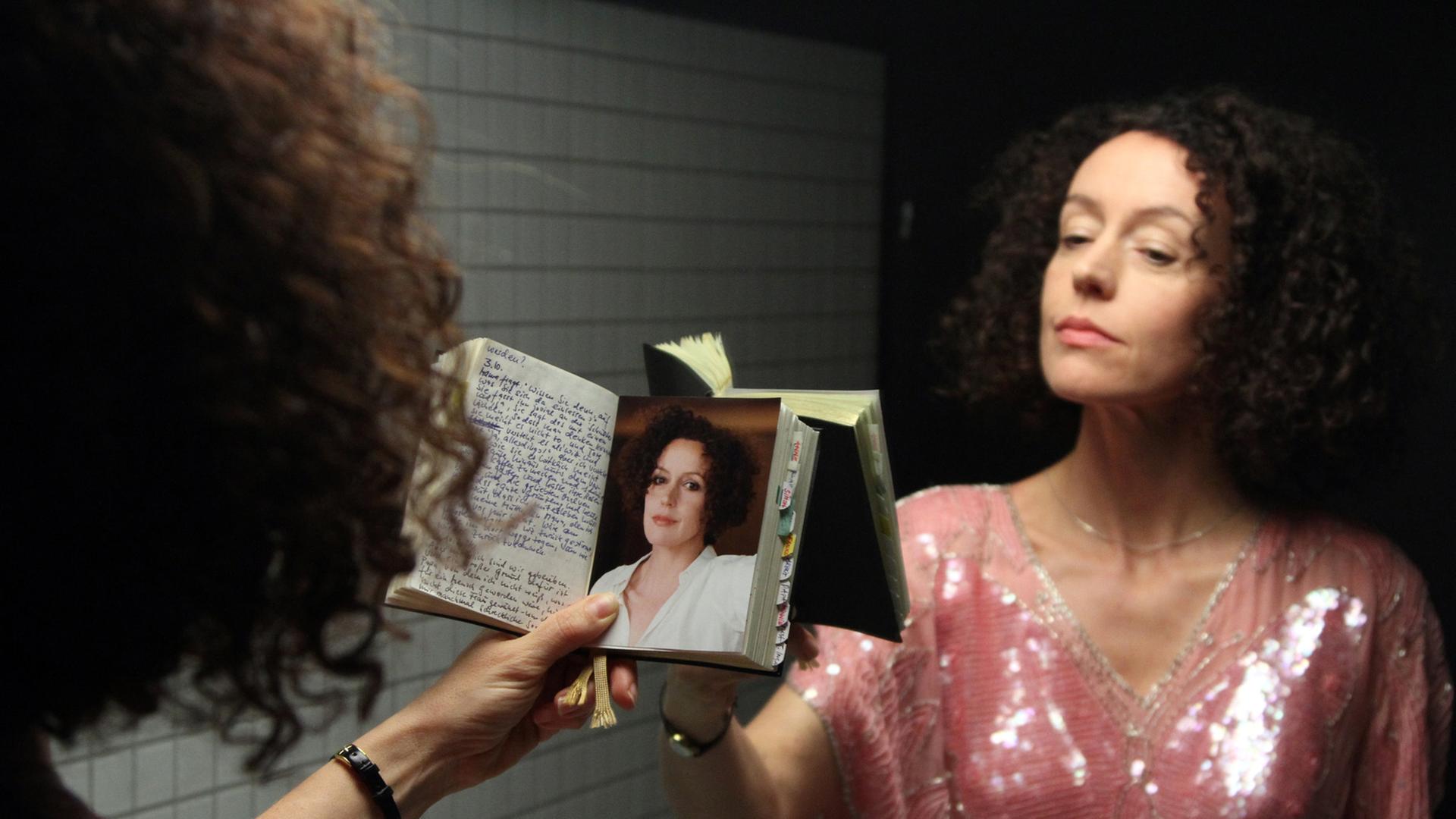 Maria Schrader als Lena Ferben in einer Szene des Films "Vergiss mein ich", in der sie ein Foto von sich vor einem Spiegel betrachtet. Maria Schrader als Lena Ferben in einer Szene des Films "Vergiss mein ich", in der sie ein Foto von sich vor einem Spiegel betrachtet.