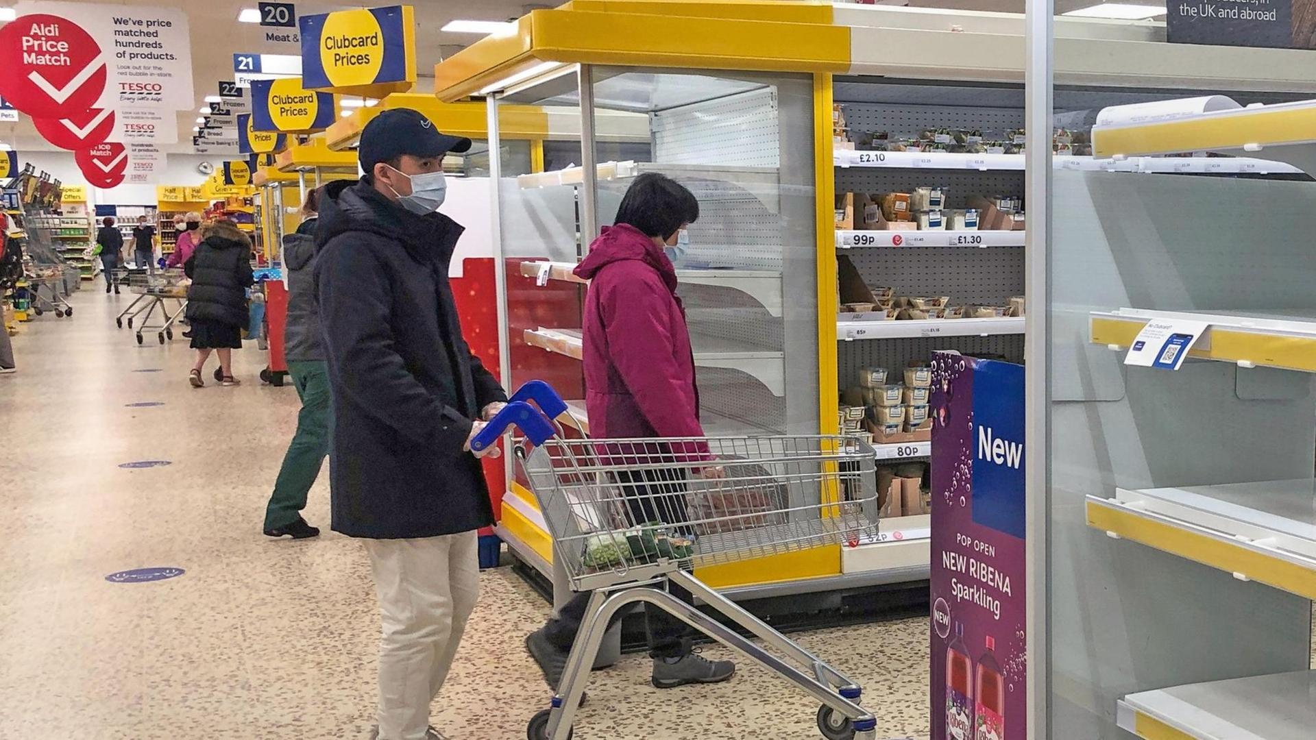 Großbritannien, Birmingham: Ein Mann geht mit Maske durch einen Tesco-Supermarkt.