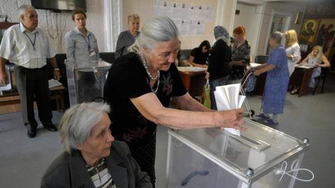 Eine ältere Frau wirft ihren Wahlzettel in eine Urne in Vinnytsia in der Ukraine