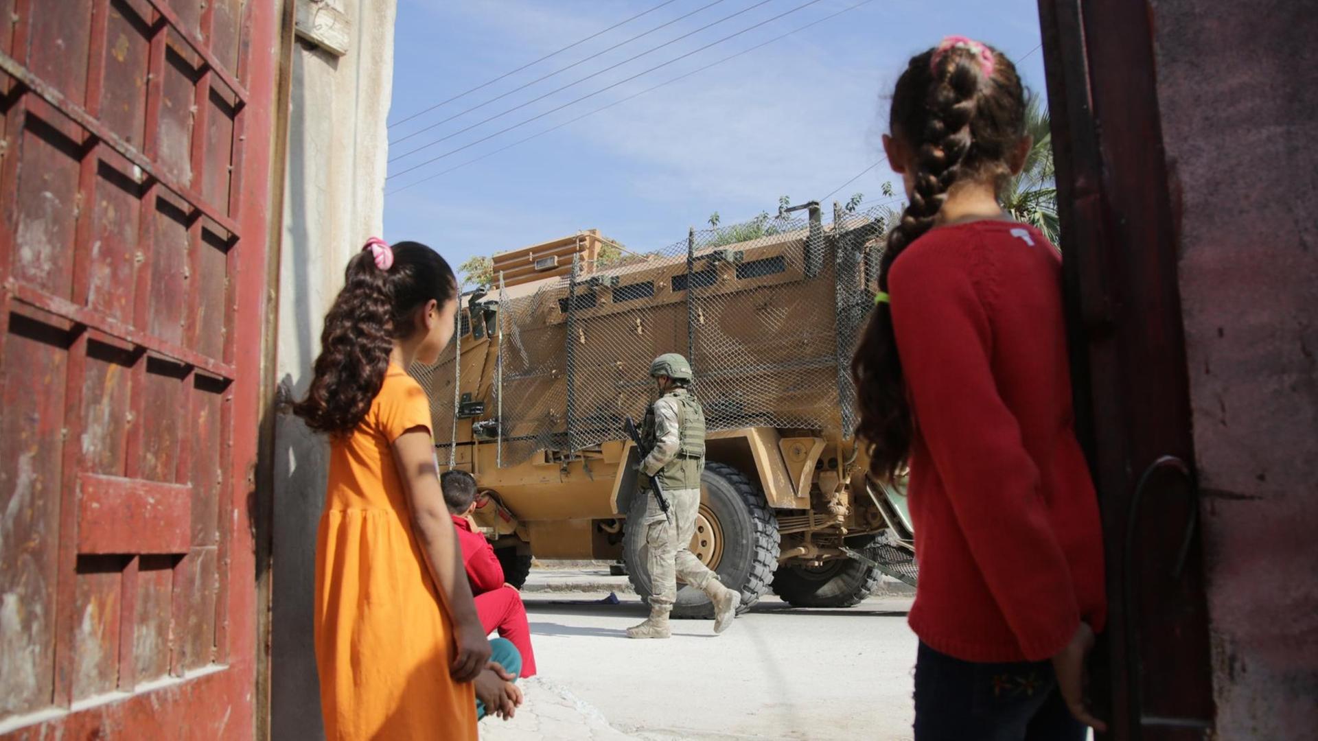 Zwei Mädchen blicken auf türkische Soldaten.