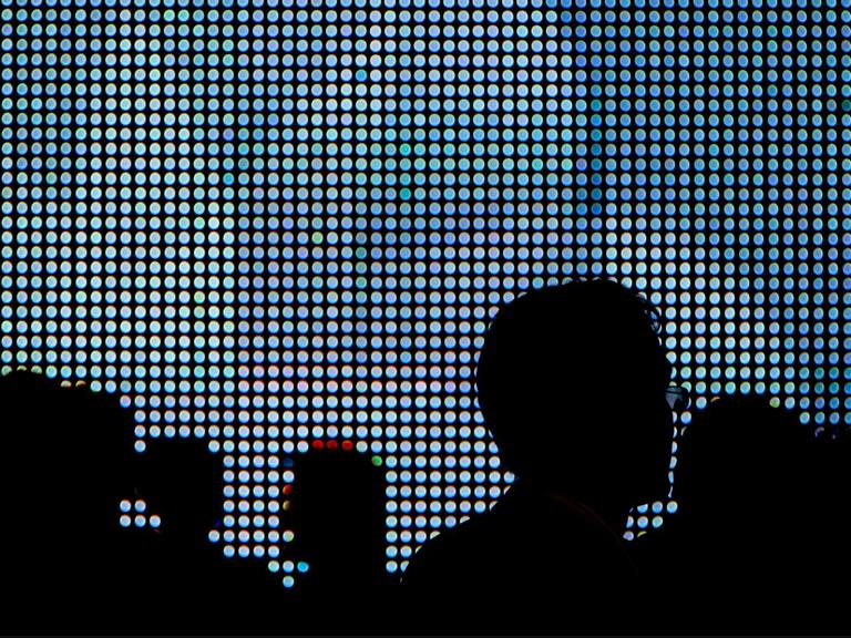 Die Schattenrisse von Messepublikum erscheinen vor den grell-blauen Leuchtdioden eines großen LED-Displays. Aufgenommen auf der Sicherheitsmesse Infosec in London am 28.04.2010. Foto: Maximilian Schönherr | Verwendung weltweit